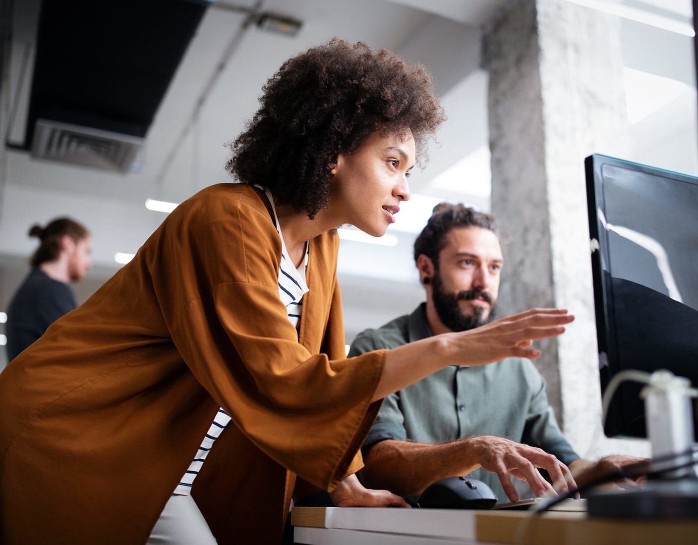 A woman and man collaborate on a computer in an office setting.